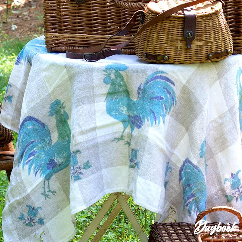 vintage table cloth with blue rooster that has two baskets on top