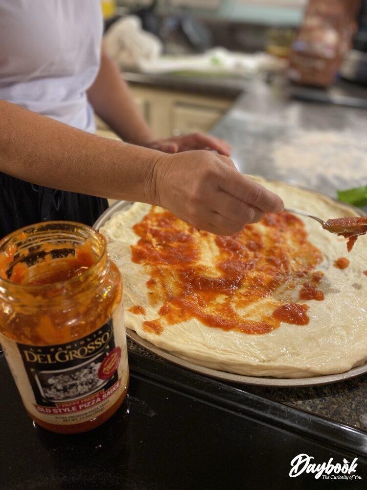 sauce being spread on pizza dough