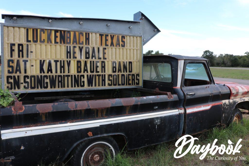 old truck in a field with a sign in the truck bed