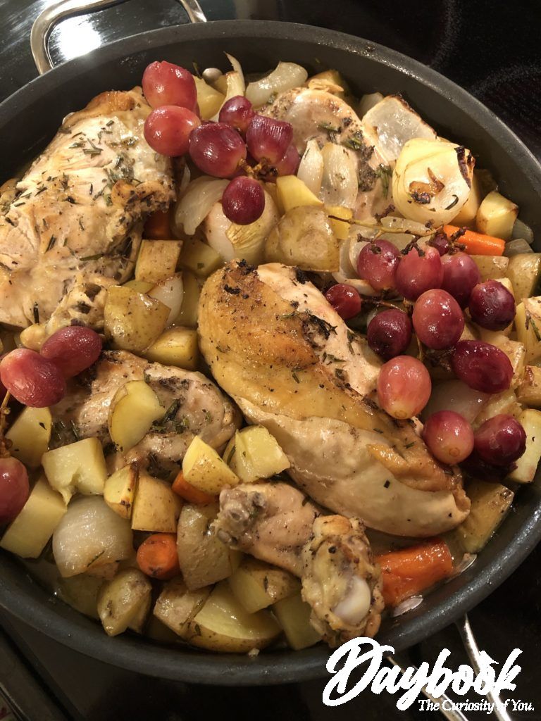 Wine-braised chicken breasts in a skillet with red grapes