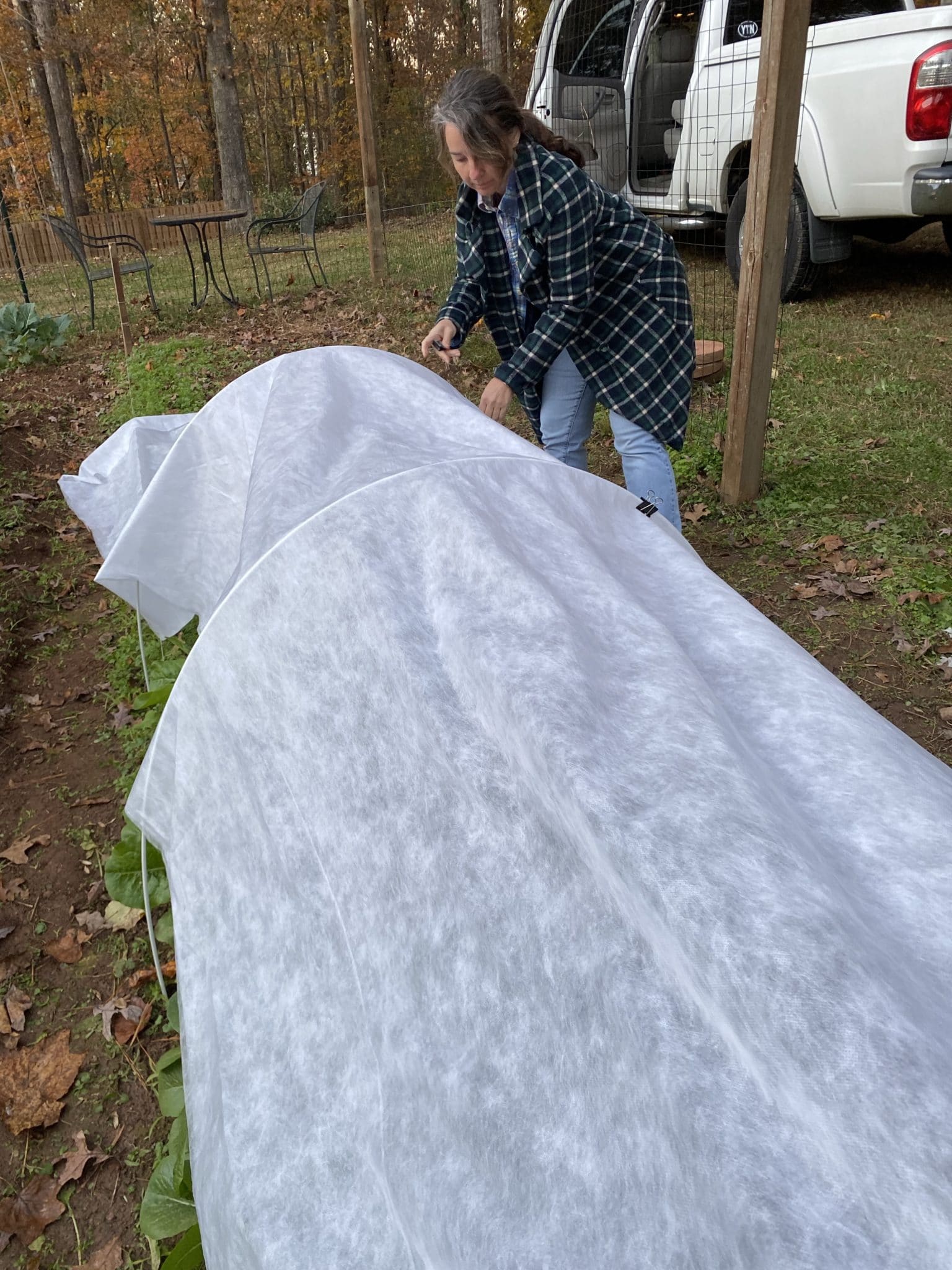 Kristy putting the agricloth over the tender greens of a winter garden