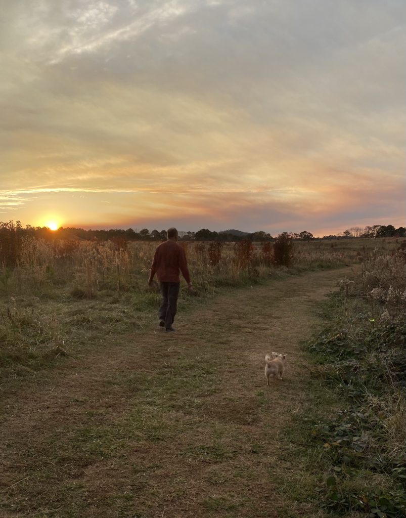 A man and his dog hiking at sunset