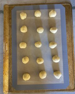 15 cookies rolled into balls on a cookie sheet