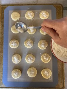 sprinkling crumble onto round cookies