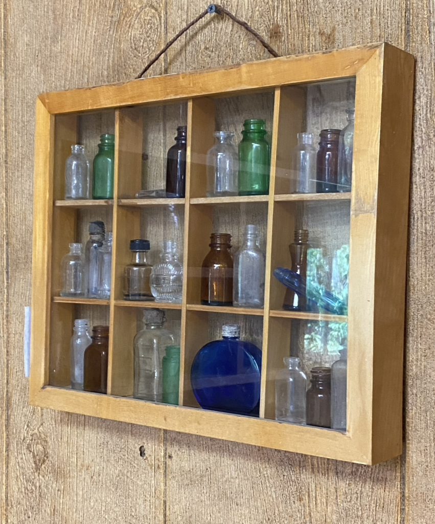 A wall shelf with a collection of colored glass jars.