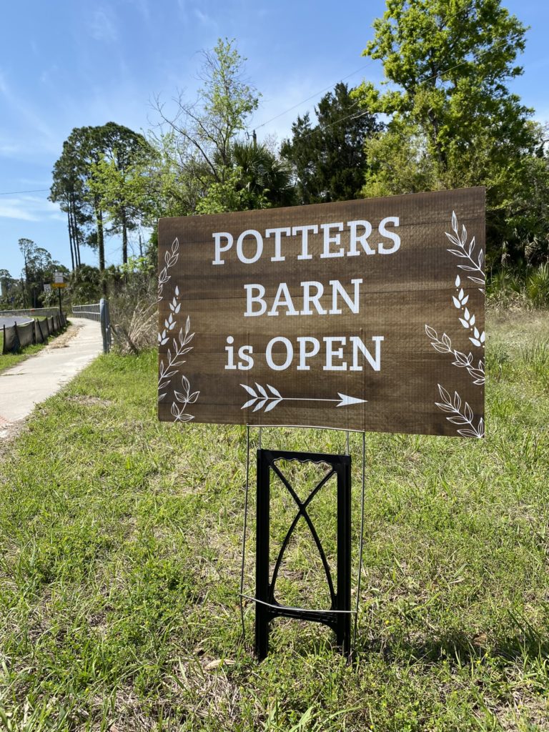 A sign reading Potter's Barn is Open with an arrow pointing right.
