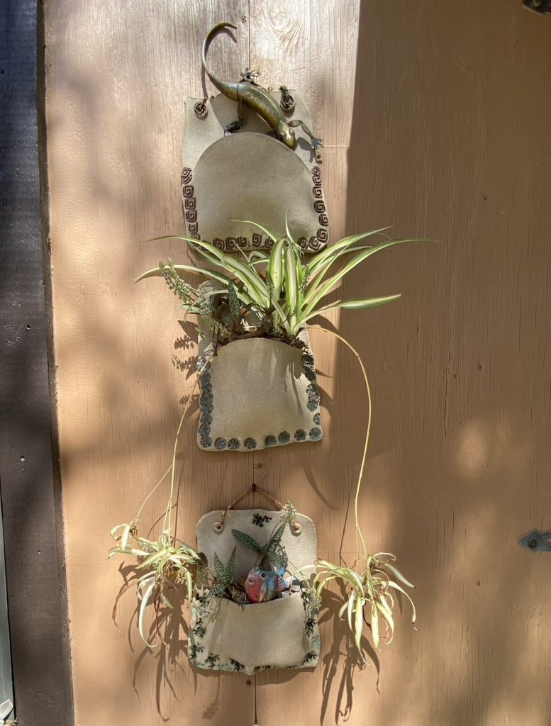 Handmade pottery plant hangers on the wall of a potter's barn.