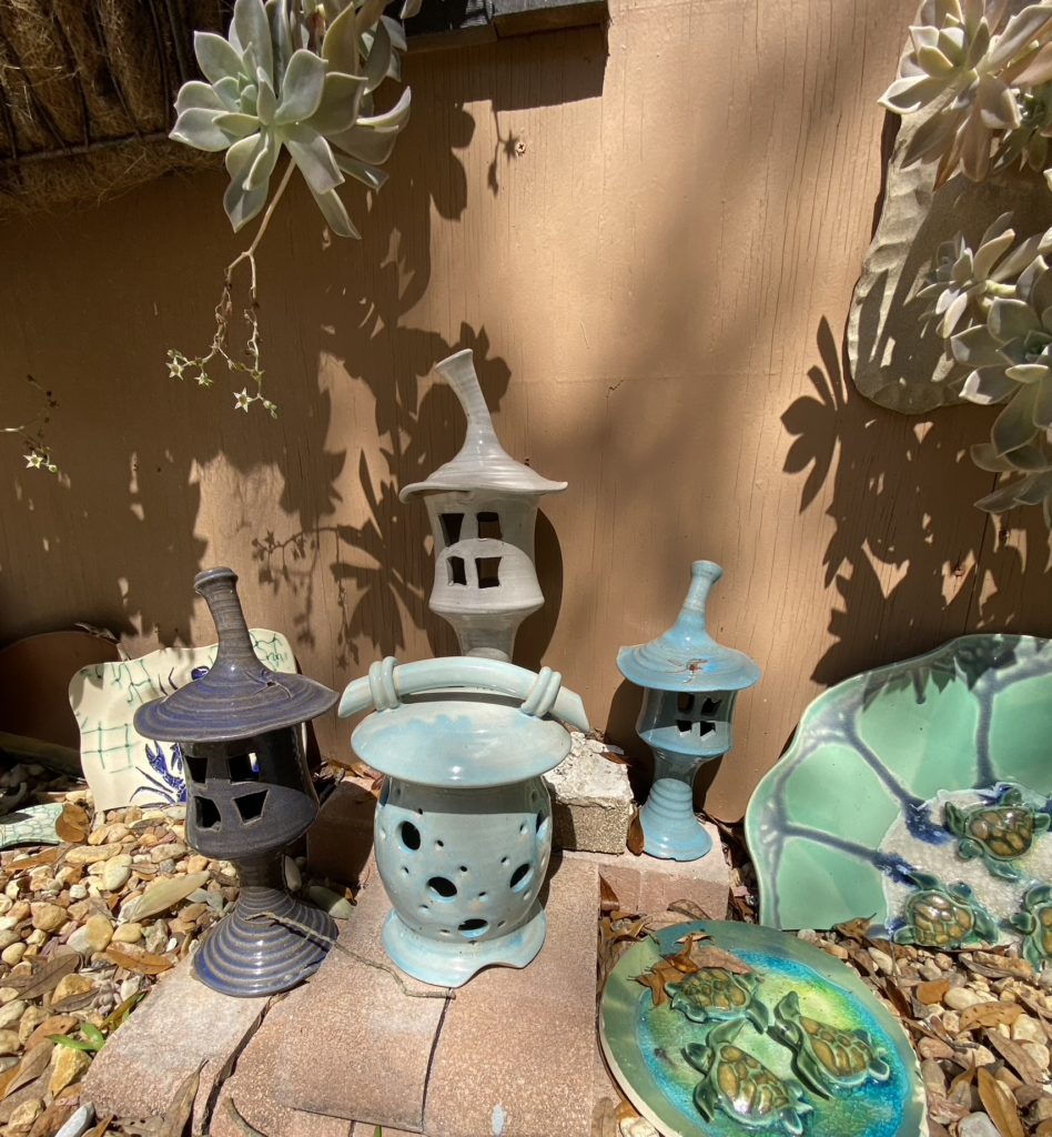 Various artistic pieces of pottery sitting on the ground beside a potter's barn