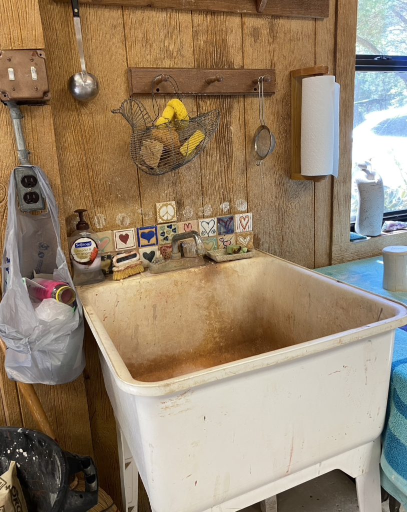 An artist's sink surrounded by collectibles.