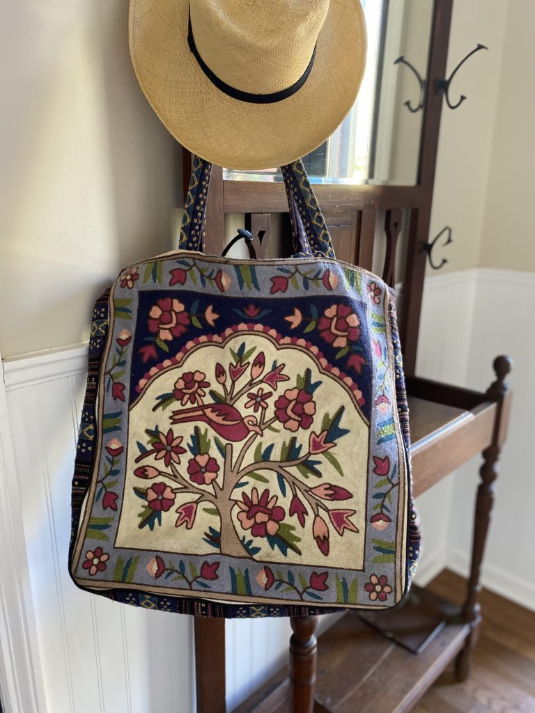 An embroidered bag and hat hanging on a hall tree.