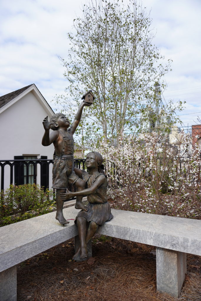 A bronze statue of a mother and child in a park.