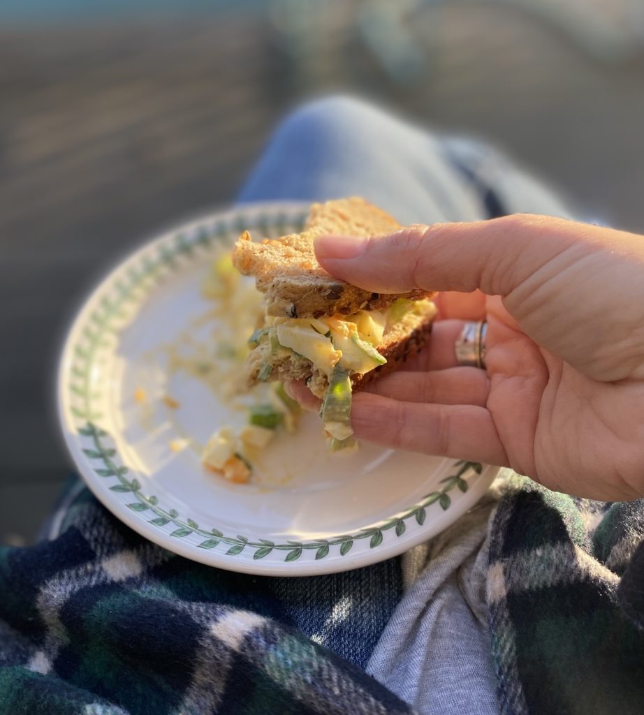 A lady's hand holding part of a simple egg salad sandwich.