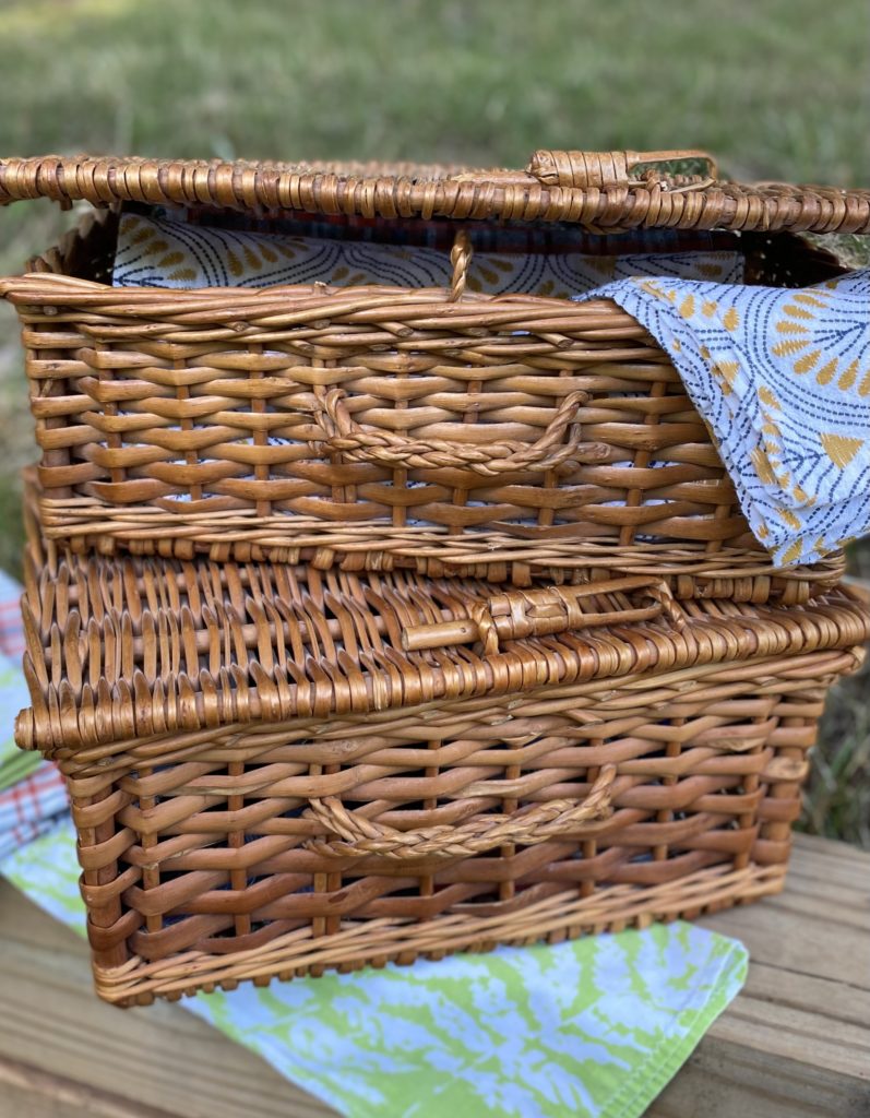 Two wicker baskets stacked outside with cloth napkins inside and outside.
