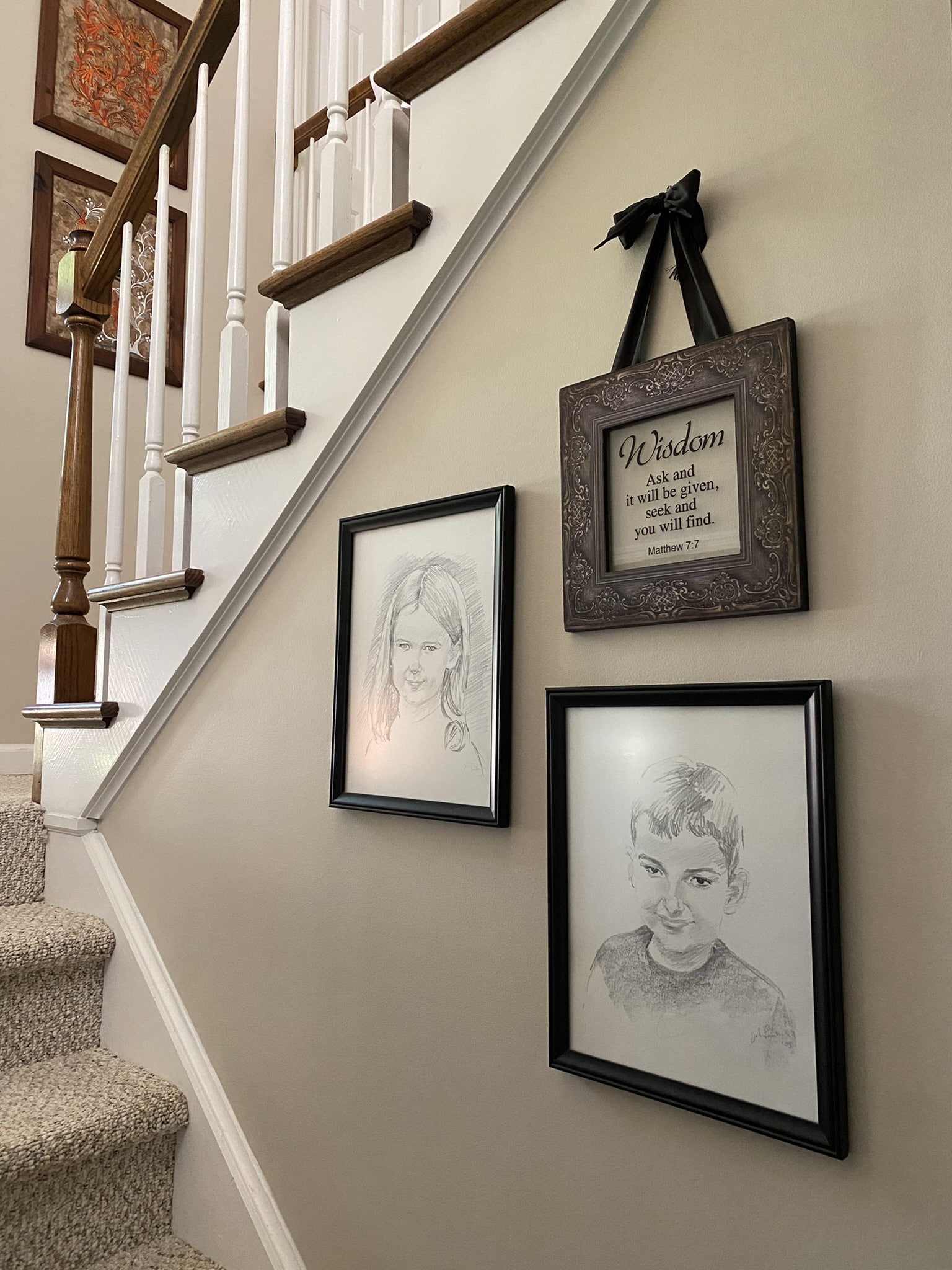 A winding staircase in a foyer with 3 pictures on the wall.
