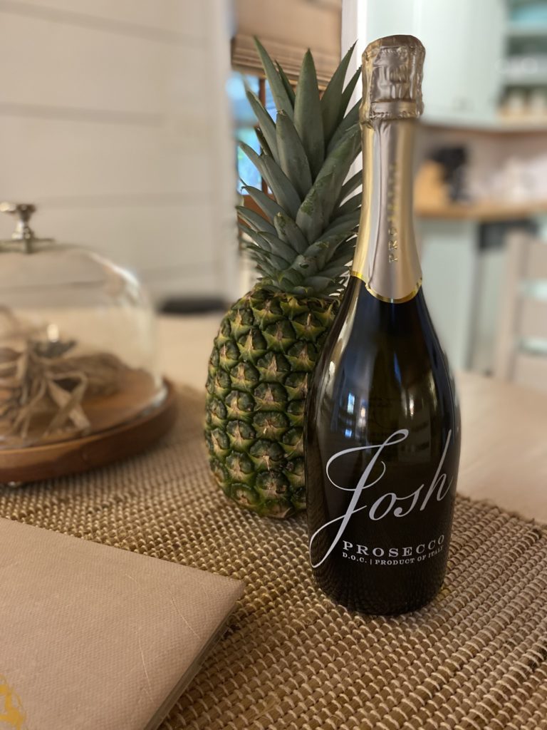 A pineapple and a bottle of wine on a kitchen table as a welcome gift.