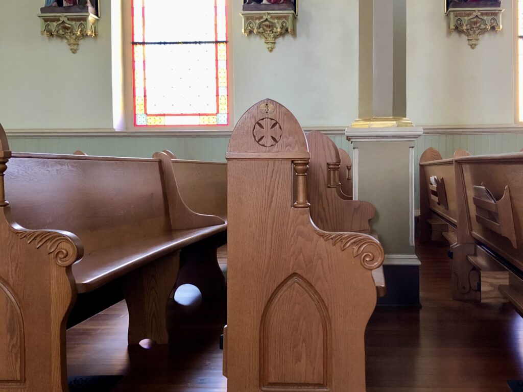 A view from the end of several wooden church pews in an old church