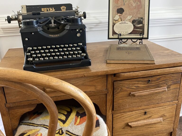 A black Royal antique typewriter on a vintage wooden desk
