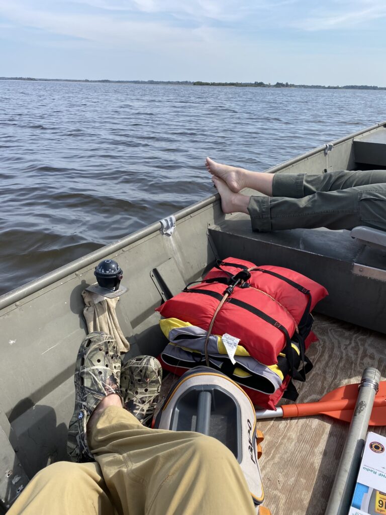The feet of two people resting in a boat out in the gulf waters
