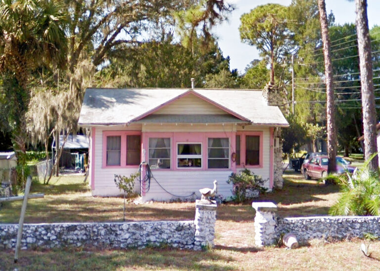 A white and pink cottage on an unassuming knoll in Yankeetown, Florida.