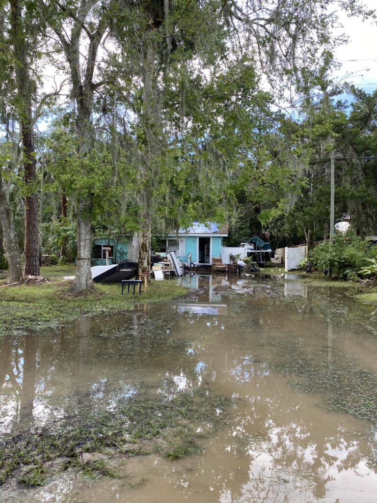 A blue house with a flooded yard after hurricane Idalia