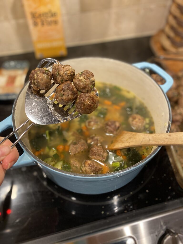 A large pot on a stovetop full of Italian Wedding Soup